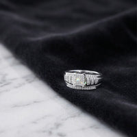 A Sterling Silver Diamond Cluster Bridal Engagement Ring rests on a black velvet cloth, placed on a white marble surface.
