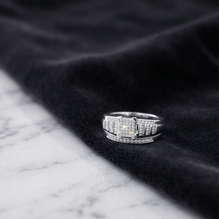 A Sterling Silver Diamond Cluster Bridal Engagement Ring rests on a black velvet cloth, placed on a white marble surface.