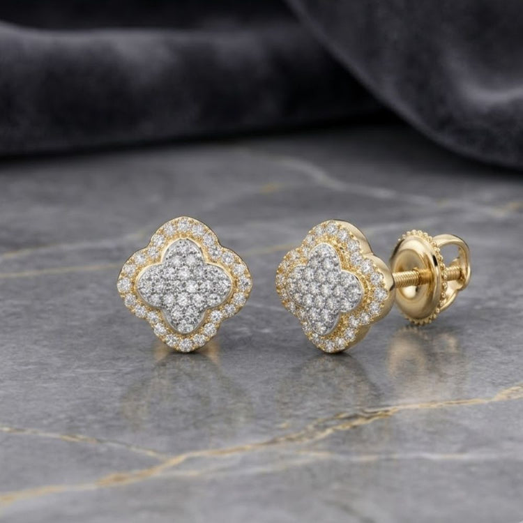 1/5 CTTW Diamond Clover Earrings in 10K Yellow & White Gold, artfully crafted in a four-leaf clover shape and pavé set with sparkling diamonds, displayed on a grey marble surface with a dark fabric background. Available in elegant white gold or classic yellow gold for a timeless touch.