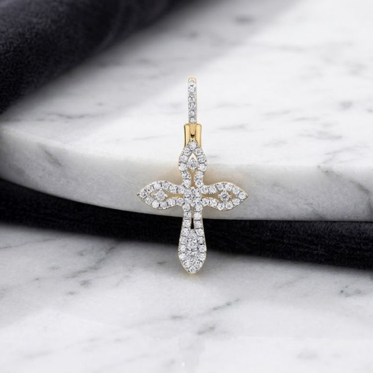 The 10K Gold 3/8 CTW Diamond Cross Pendant is displayed on a white marble surface with a black fabric nearby, accentuating its sparkling, intricate design.