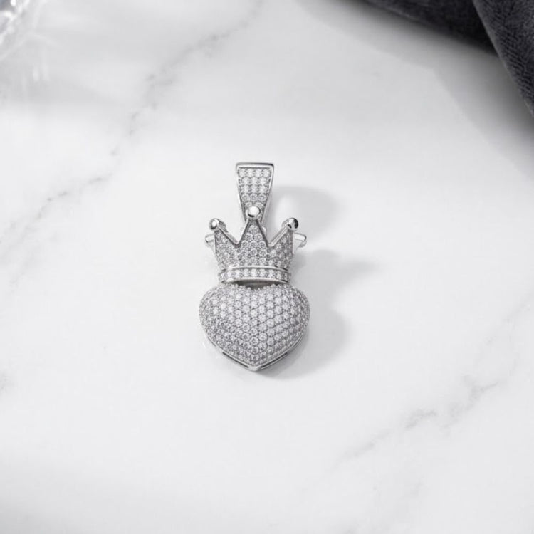 The 925 Sterling Silver Crown Heart Pendant features a crown heart charm adorned with delicate diamonds, beautifully set on a heart-shaped pendant crafted from genuine 925 sterling silver. Displayed elegantly on a white marble surface, this stunning piece showcases a regal design that is ideal for anyone who cherishes refined elegance in fine jewelry.