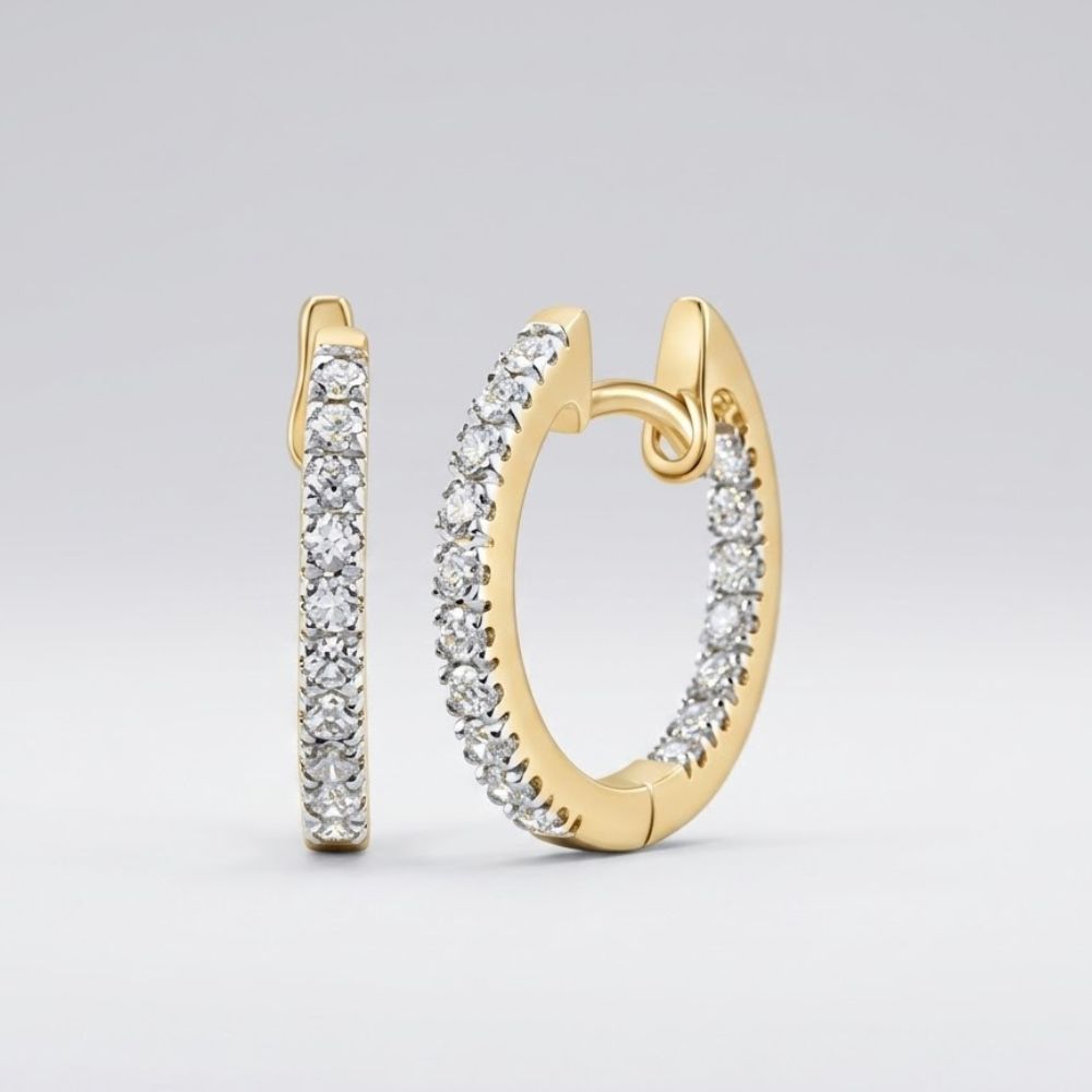 A pair of 10K Gold Diamond Inside Outside Hoop Earrings 1/4 Cttw, encrusted with round diamonds, is shown upright and lying flat on a light, neutral background.