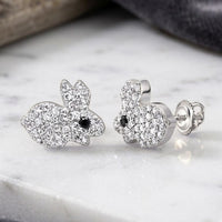 Two small, silver bunny-shaped earrings encrusted with clear gemstones and featuring striking black diamond eyes—these charming 10K Gold Black Diamond Earrings (1/4 CTW) are beautifully displayed on a marble surface.