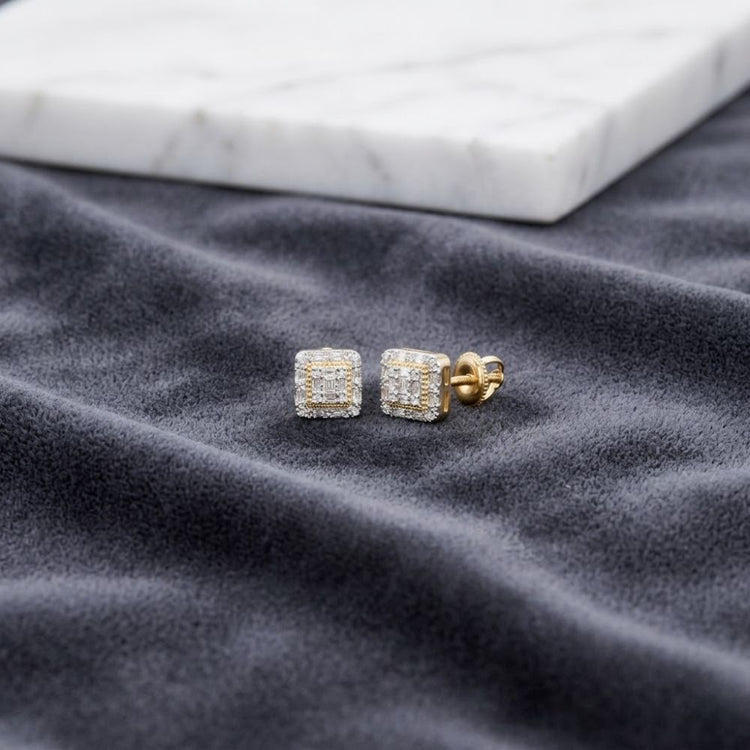 1/6 CTW Natural Diamond Baguette Earrings are displayed on a soft, dark fabric surface, with a white marble slab in the background. These stunning 10K gold earrings beautifully showcase natural diamond baguette accents, adding elegance to any collection.