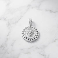 The Diamond Lion Face Cuban Charm 1/2CT Sterling Silver—a bold sterling silver men’s pendant adorned with sparkling diamonds and showcasing a striking lion’s head design—rests elegantly on a white marble surface, embodying the essence of Cuban round men's jewelry.