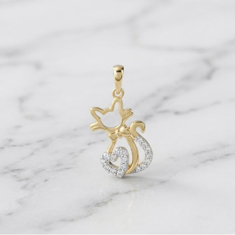 The 1/10 CTW Diamond Heart Cat Pendant in 10K Gold, shaped like a cat with a sparkling bow and tail, makes the perfect cat lover’s gift and looks stunning on a white marble display.