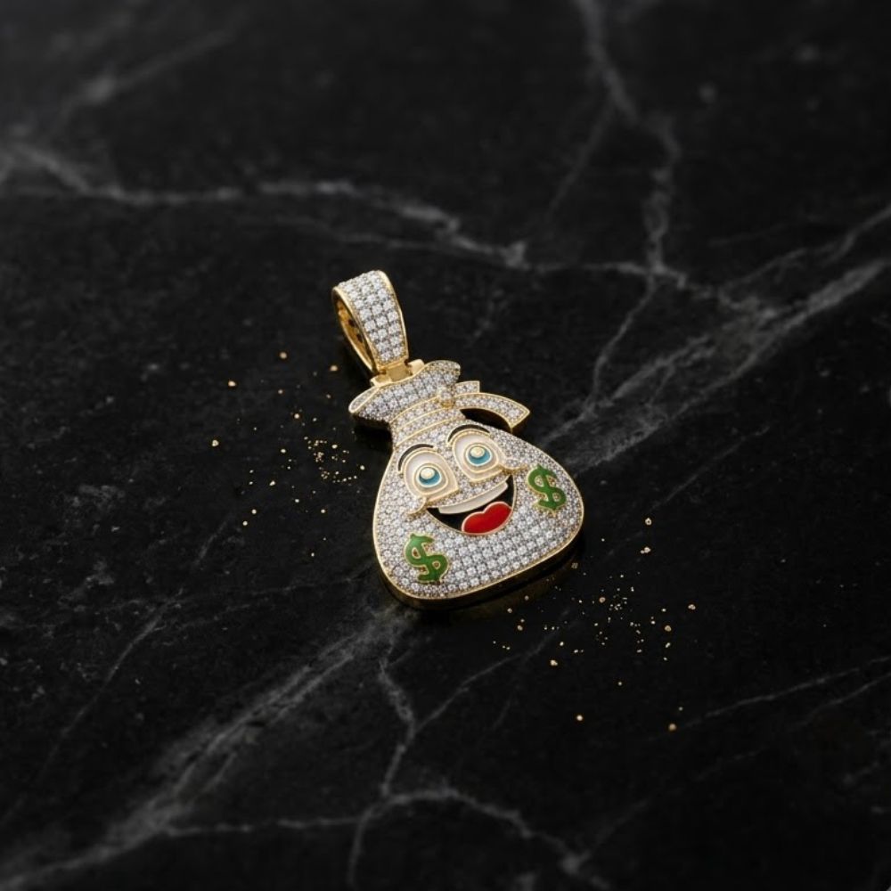 The 10K Gold Diamond Money Bag Men’s Charm 1/2CTW features a smiling face with dollar signs and sparkling details, crafted in yellow gold—a bold, natural diamond jewelry piece. Displayed on black marble with scattered gold glitter.
