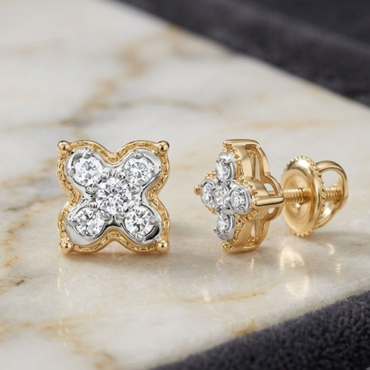 Introducing the 1/6CTW Natural Diamond Clover Earrings in 10K Gold—exquisite clover-shaped studs, each adorned with four sparkling natural diamonds. Presented on a marble surface with a soft dark cloth in the background, these elegant earrings embody the timeless allure of diamond clover designs.