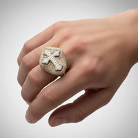 A hand showcases the Cross Diamond Signet Ring – 7.20 CT Baguette and Pavé Design, a bold men's gold ring with a striking, diamond-encrusted cross on top for maximum brilliance.