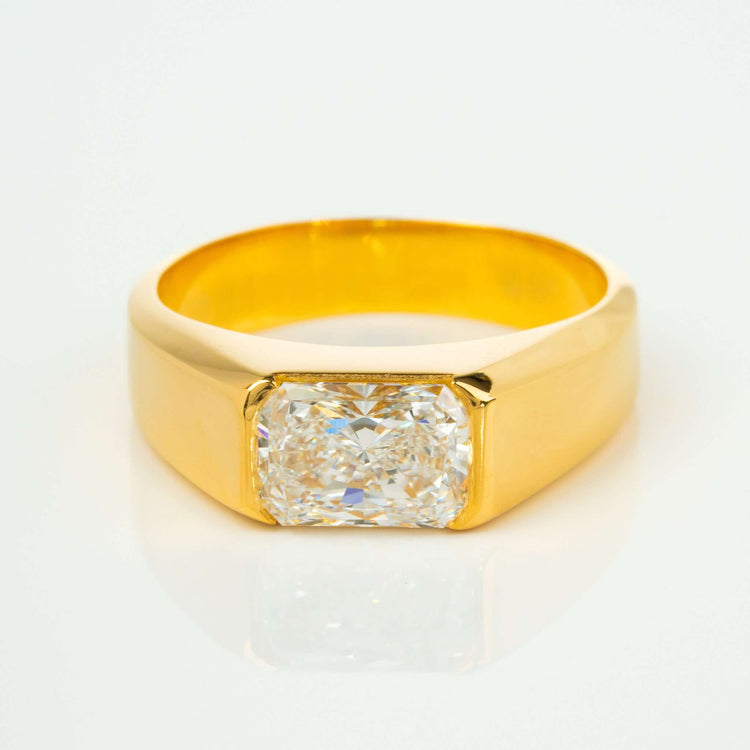The 2 CT Radiant-Cut Diamond Statement Ring features a bold 18K yellow gold wide band with a large rectangular radiant-cut diamond at the center, displayed against a white background.