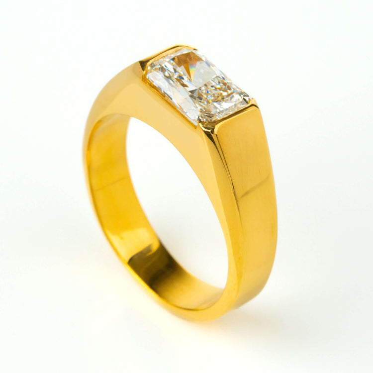 The 2 CT Radiant-Cut Diamond Statement Ring showcases a thick 18K yellow gold band with a horizontally set radiant-cut diamond, displayed on a plain white background.