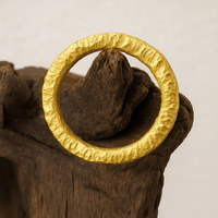 The 24k - 4mm Hammered Donut Ring, featuring a textured finish, is displayed on rugged, weathered wood with a neutral background.
