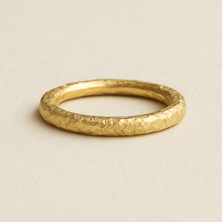 The 24k - 4mm Hammered Donut Ring features a textured, hammered finish and an elegant, stackable band style, displayed on a neutral light beige surface.