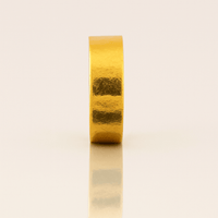 The 6mm Flat Band Ring -24k stands upright on a reflective surface against a light beige background.
