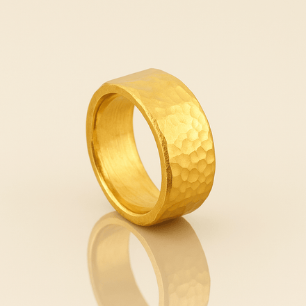 The 10mm, 24k 1oz Hammered Flat Band features a hammered texture and matte finish, elegantly displayed upright on a light beige background to highlight its comfort-fit design.