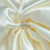 The 2.08ct Radiant Lab Diamond Solitaire Engagement Ring in 14k solid gold rests on smooth ivory satin, with elegant folds highlighting its sparkling beauty.