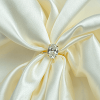 A 1.72ct oval-cut lab diamond shines atop a 14k solid yellow gold band, capturing the timeless elegance of gold engagement rings as it rests on softly draped creamy white satin.