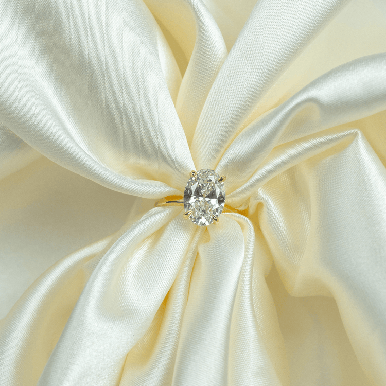 A 1.72ct oval-cut lab diamond shines atop a 14k solid yellow gold band, capturing the timeless elegance of gold engagement rings as it rests on softly draped creamy white satin.