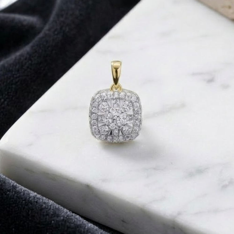 The 14K Gold 1/2 Ctw Diamond Cushion Pendant, featuring a floral-inspired design and sparkling natural diamonds, rests on a white marble surface with black fabric elegantly draped nearby.