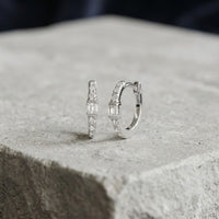 1/8CTW Natural Diamond Hoop Earrings 10K Gold: a pair of small 10K yellow gold hoop earrings, each featuring a centered baguette diamond flanked by natural diamond round accent stones.