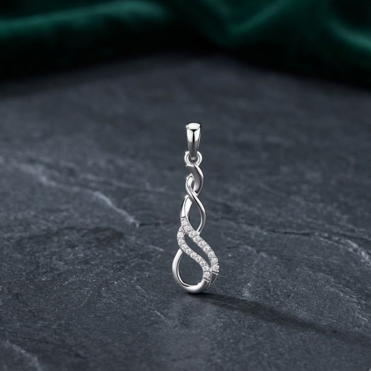 The 1/20 CTW Diamond Infinity Pendant in 10k gold, featuring a twisting infinity design adorned with sparkling diamonds, rests on a dark textured surface with a green velvet background.