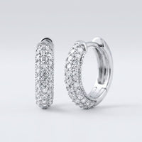 A pair of 3/4CTW natural diamond hoop earrings in 14k gold, sparkling with multiple rows of diamonds, displayed against a plain light grey background.