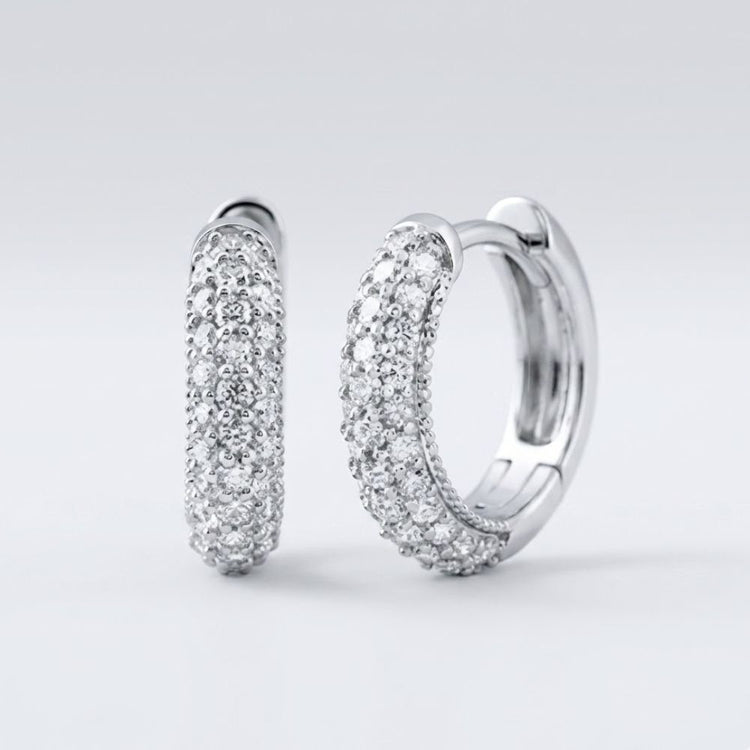 A pair of 3/4CTW natural diamond hoop earrings in 14k gold, sparkling with multiple rows of diamonds, displayed against a plain light grey background.