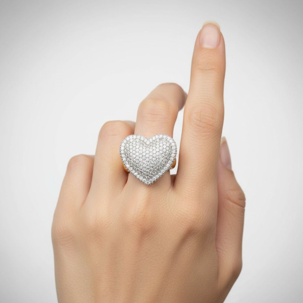 A hand with a light skin tone wears the Iced-Out Heart Cluster Ring 5.46 CT Diamond - 14k Yellow Gold on the middle finger, shown against a plain white background.