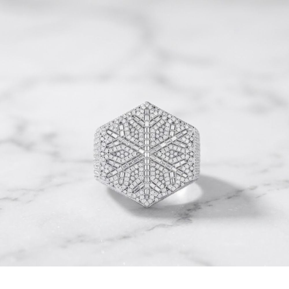 The 925 Silver Moissanite Snowflake Ring features a hexagonal design with an intricate snowflake pattern, set with sparkling moissanite stones, displayed on a white marble surface.