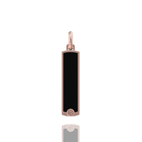 The 14k Gold Black Enamel Tag Pendant features a rectangular black enamel center, a rose gold frame, and a small round accent at the bottom, shown on a white background with a subtle reflection beneath it.