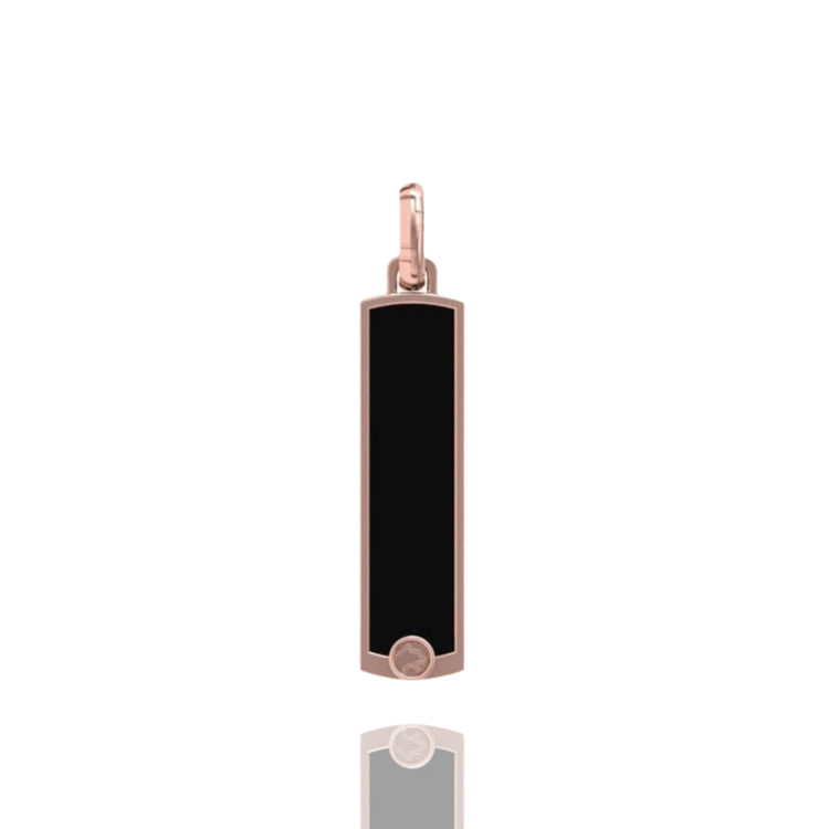 The 14k Gold Black Enamel Tag Pendant features a rectangular black enamel center, a rose gold frame, and a small round accent at the bottom, shown on a white background with a subtle reflection beneath it.