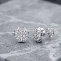 A pair of 1/10CTW natural diamond round gift earrings in 10K gold, displayed on a gray marble surface.