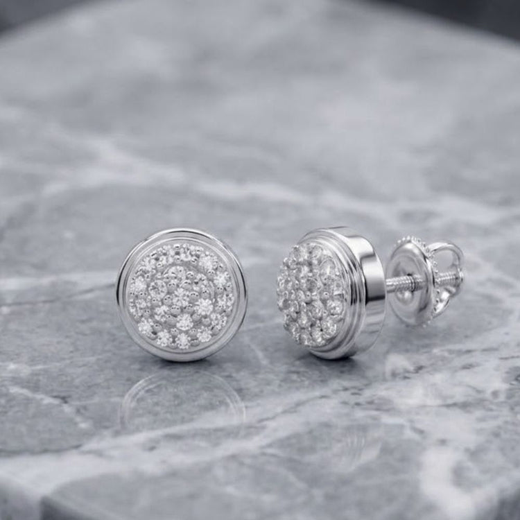 A pair of 1/10CTW natural diamond round gift earrings in 10K gold, displayed on a gray marble surface.