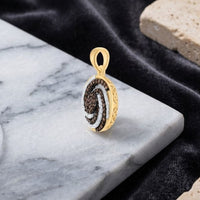 The 10k Yellow Gold Cognac Diamond Pendant 1/2 CTTW showcases black, brown, and white natural diamonds arranged in a swirling pattern, elegantly displayed on a white marble surface with a dark fabric and beige textured stone in the background. Crafted from 10k yellow gold, this sophisticated pendant embodies timeless elegance.