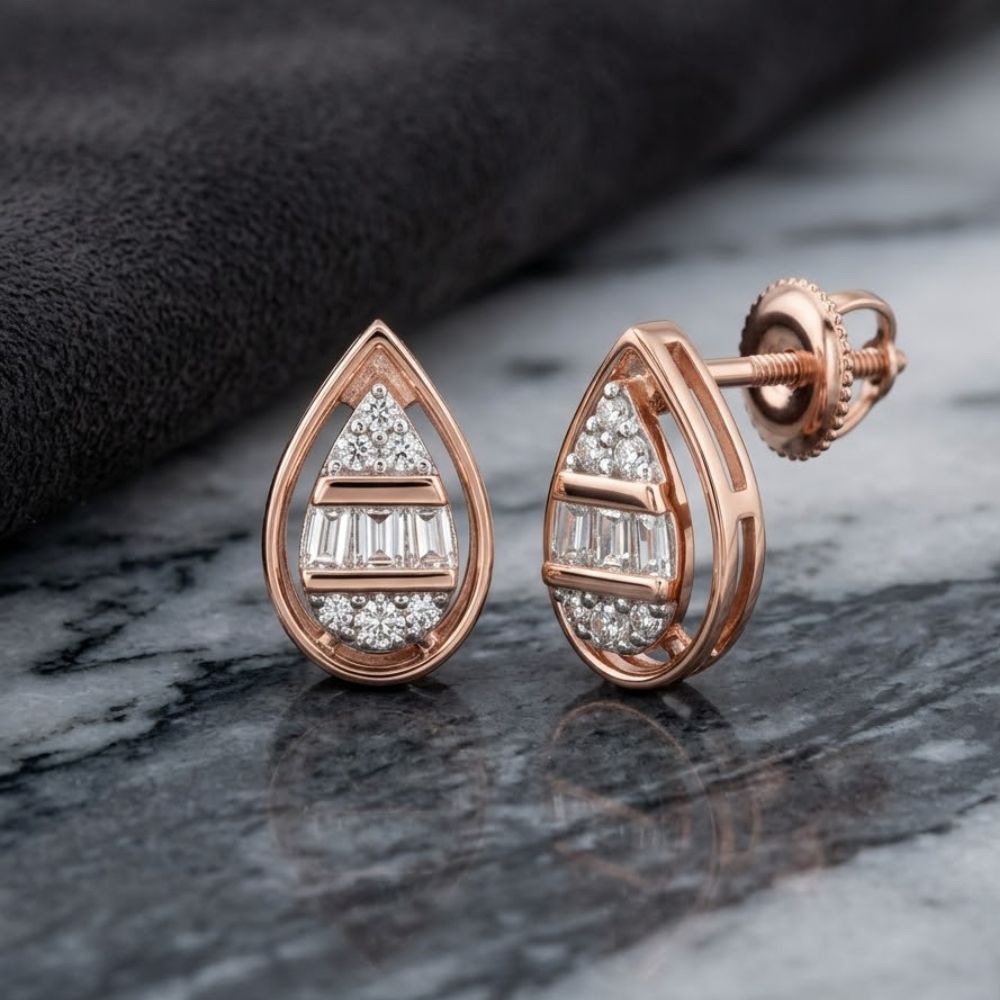 A pair of 1/10 CTW Natural Diamond Pear Earrings in 10k Gold, shown on a marble surface beside a folded dark cloth.