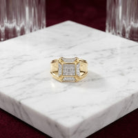A 10K Yellow Gold Diamond Cluster Ring 1/4CT is displayed on a white marble slab, with crystal glasses and a burgundy background behind it.