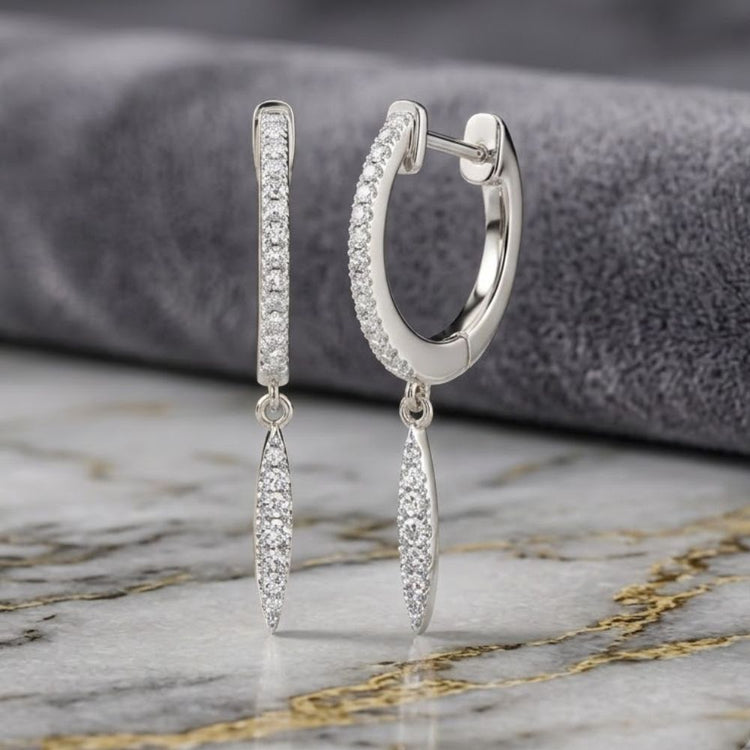 A pair of 10k White Gold Diamond Drop Dangle Earrings featuring diamond-adorned marquise-shaped pendants, showcased on a marble surface against a gray fabric backdrop.