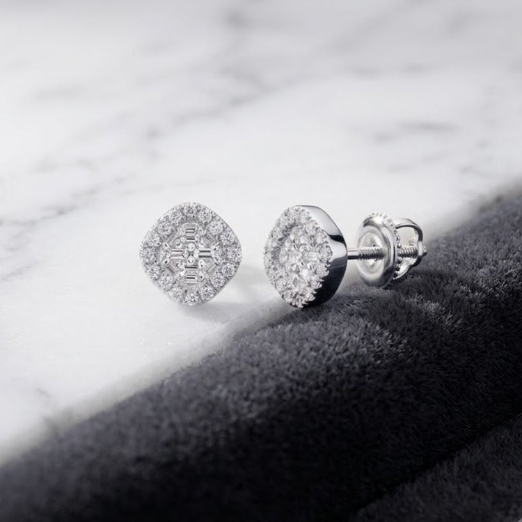 A pair of 1/6CTW Clover Diamond Earrings in 10k gold, featuring secure screw-back posts and elegantly displayed on a marble surface beside black textured fabric, exude timeless elegance—perfect for those who appreciate the refined allure of fine gold jewelry.