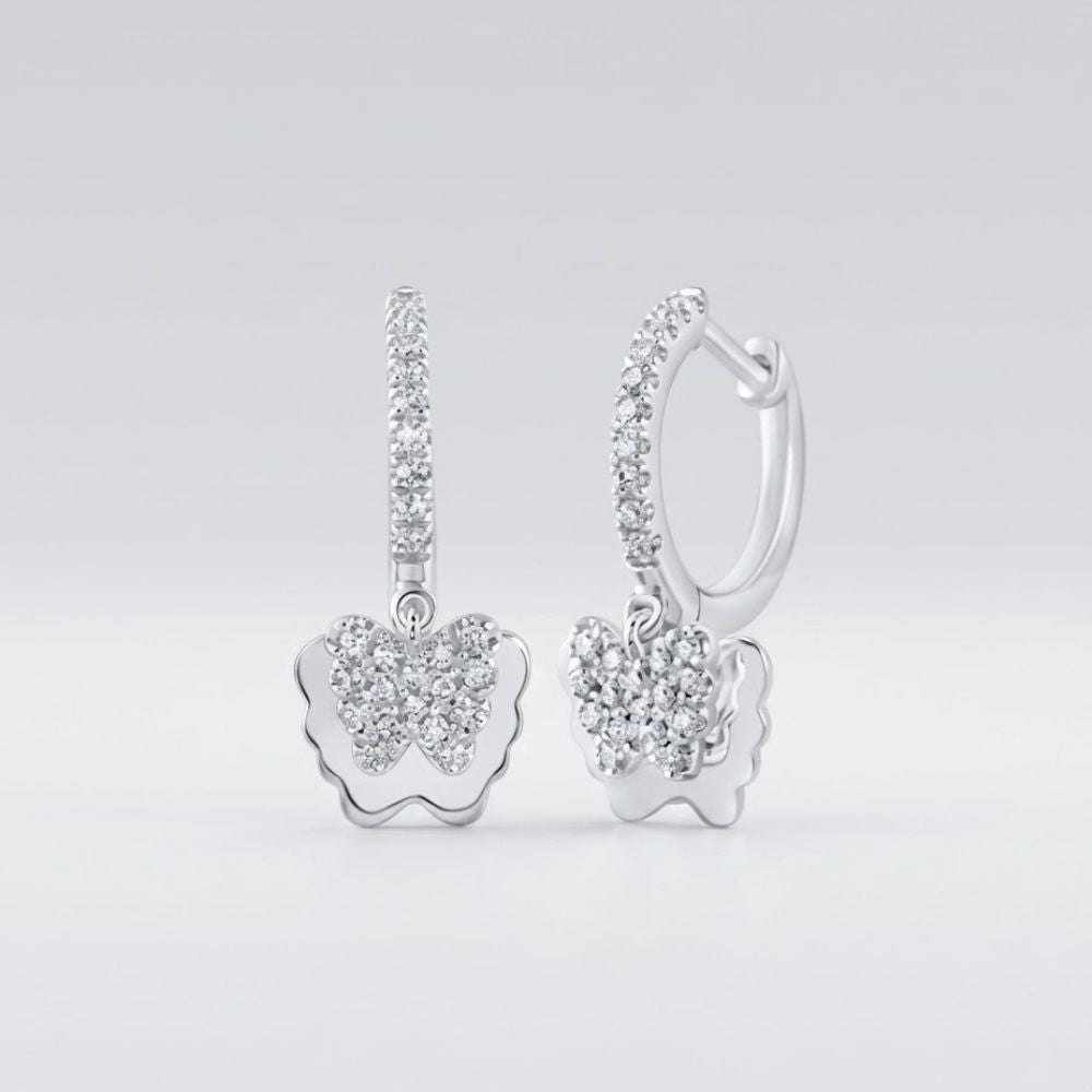 The 10k Gold Diamond Butterfly Hoop Earrings 1/4 Cttw feature butterfly-shaped pendants and hoops, both encrusted with sparkling diamonds and set against a smooth, light gray background.