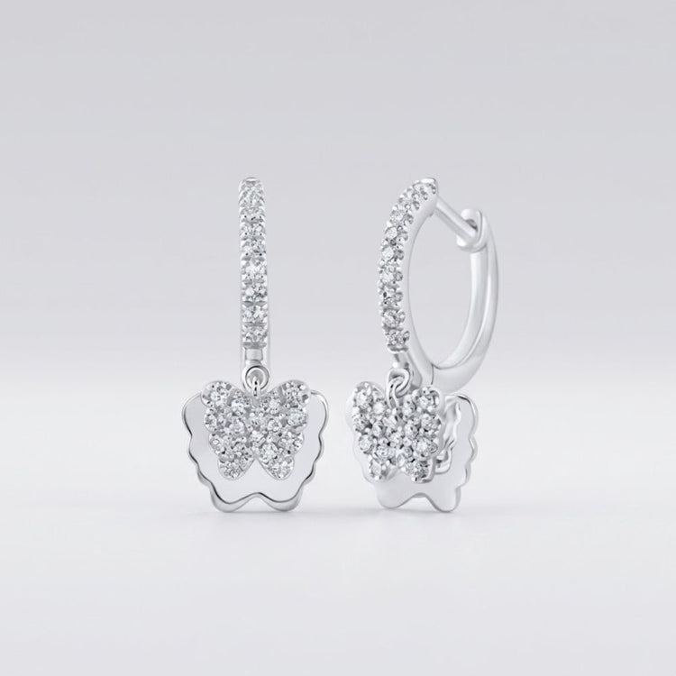 The 10k Gold Diamond Butterfly Hoop Earrings 1/4 Cttw feature butterfly-shaped pendants and hoops, both encrusted with sparkling diamonds and set against a smooth, light gray background.