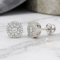 A pair of 14K Gold Round Diamond Cluster Earrings, totaling 5/8 carat, displayed on a white marble surface.