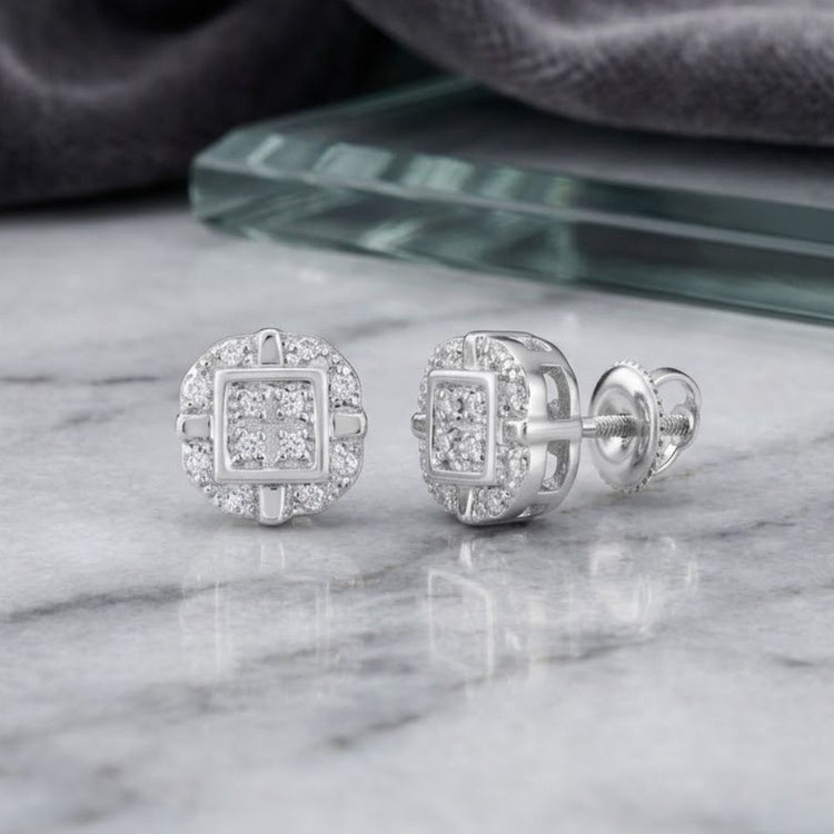 A pair of 10k Gold Diamond Rounded Square Earrings (1/12 Cttw) with a concentric square and round design, set in white metal, displayed on a marble surface.