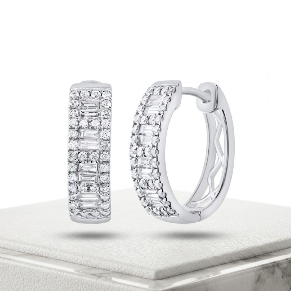 The 5/8CTW Diamond Baguette Hoop Earrings in 14K Gold feature rows of round and baguette-cut diamonds, shown on a white textured platform against a plain white background.