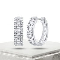 The 5/8CTW Diamond Baguette Hoop Earrings in 14K Gold feature rows of round and baguette-cut diamonds, shown on a white textured platform against a plain white background.