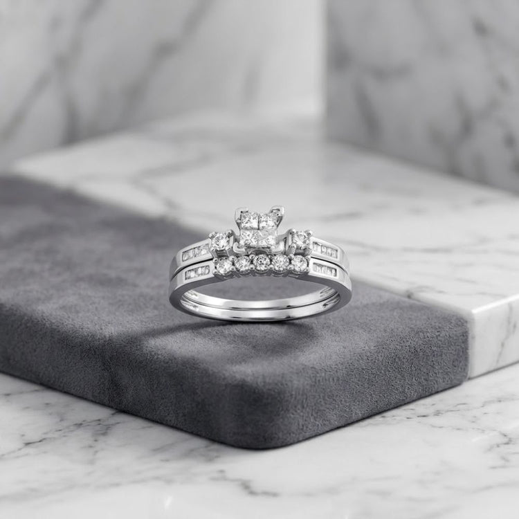 The 10k Gold Princess Diamond Bridal Ring Set 3/8 Cttw is elegantly displayed on a gray velvet surface against a marble background, featuring a radiant white gold engagement ring adorned with multiple sparkling princess-cut diamonds and completed by a matching wedding band for a sophisticated ensemble.