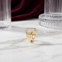 A 10k Gold Diamond Cross Cluster Ring 1/3 Cttw is displayed upright on a marble surface, showcasing a cluster of sparkling diamonds at its center. In the background, tall glass columns and deep burgundy velvet fabric enhance the elegant presentation.