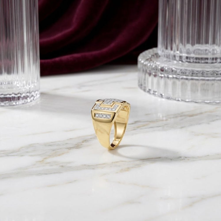 A 10k Gold Diamond Cross Cluster Ring 1/3 Cttw is displayed upright on a marble surface, showcasing a cluster of sparkling diamonds at its center. In the background, tall glass columns and deep burgundy velvet fabric enhance the elegant presentation.