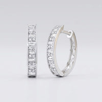 The 1/2CTW Diamond Baguette Hoop Earrings in 14K gold feature a row of sparkling baguette diamonds along the front. Shown: one earring faces forward, the other from the side, against a light gray background.