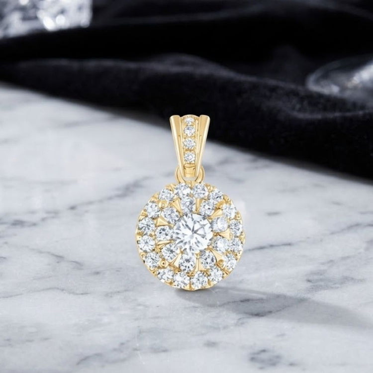 The 3/4 CTW Diamond Round Pendant in 14K Gold, showcasing a circular array of brilliant diamonds totaling 3/4 carat, is elegantly displayed on a marble surface with a softly blurred black cloth background.