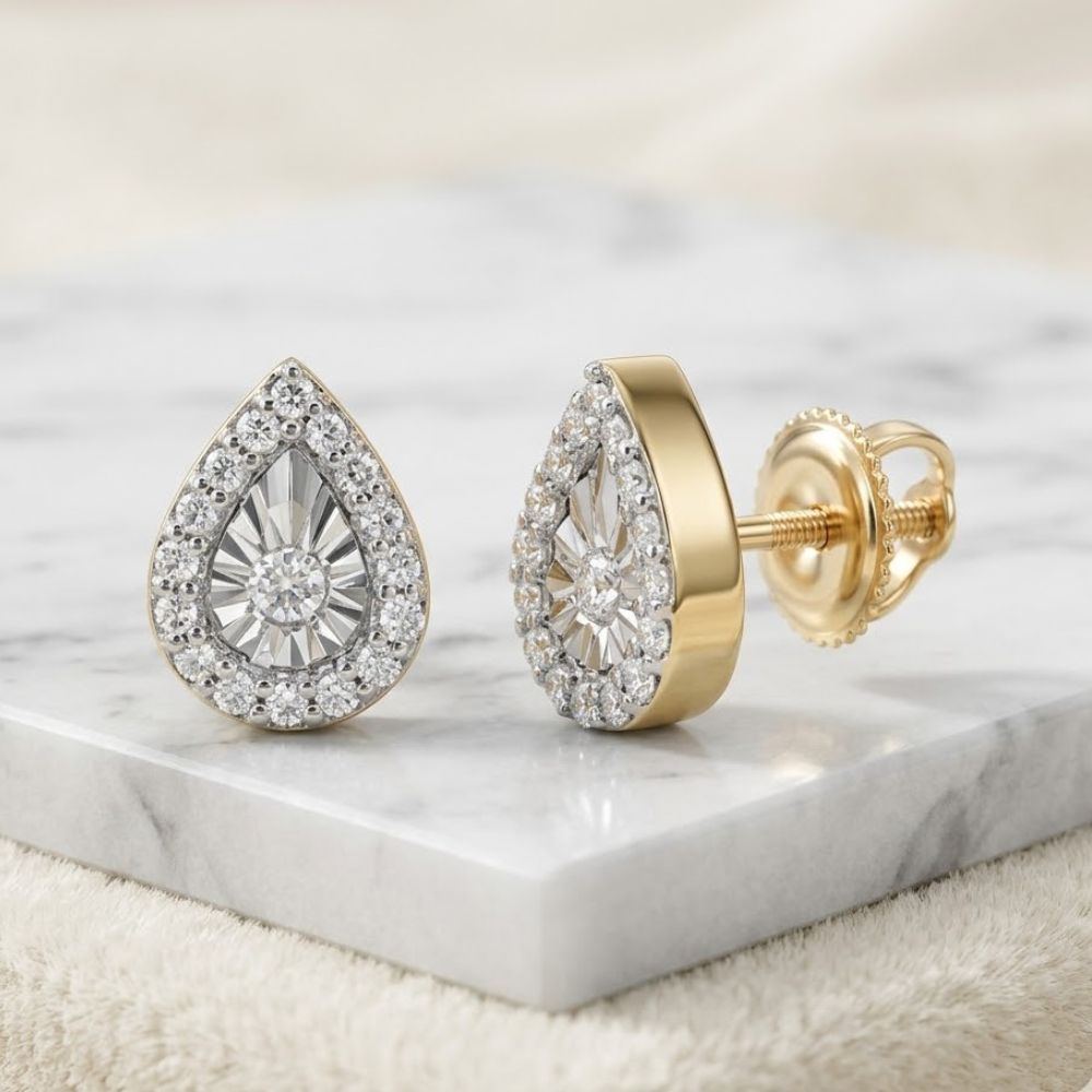 1/10CTW Natural Diamond Pear Earrings in 10K gold, featuring teardrop-shaped diamonds surrounded by smaller stones, are elegantly displayed on a white marble surface.